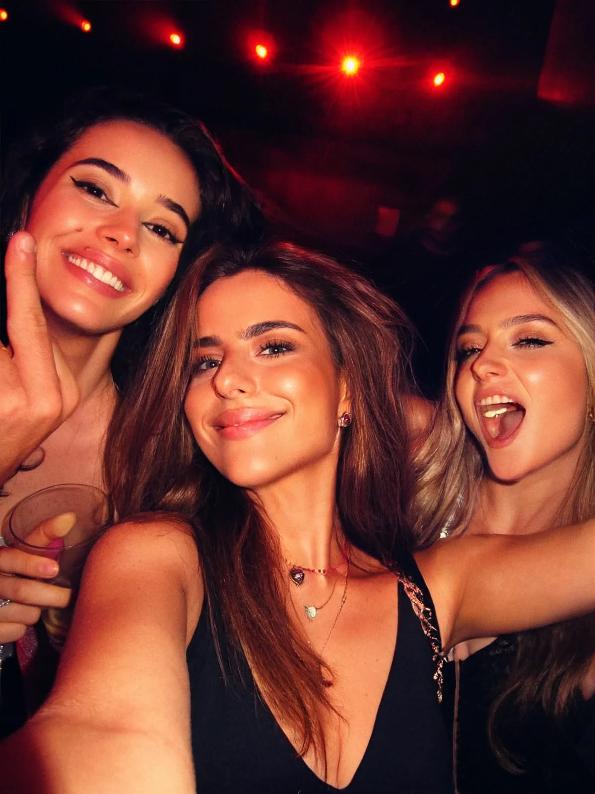 Three friends smiling together during a night out